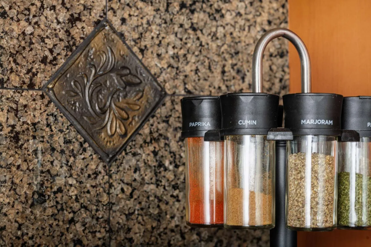 A warm and inviting kitchen scene featuring spice jars neatly arranged and vibrant decorative tilework as a backsplash. The space exudes energy and anticipation for shared meals, hinting at convivial gatherings and lively conversations.