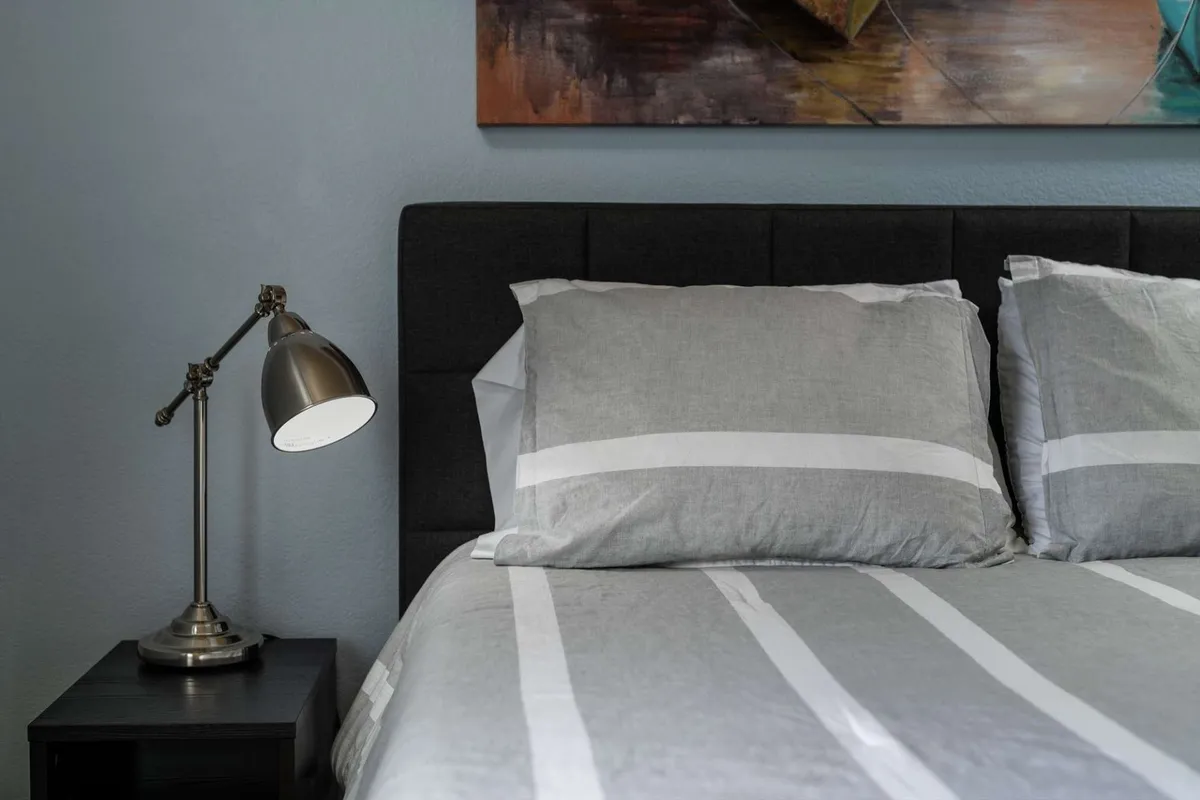 A tranquil bedroom with a neatly made bed, soft lighting from a bedside lamp, and tasteful wall art, creating an atmosphere perfect for relaxation and restful sleep.