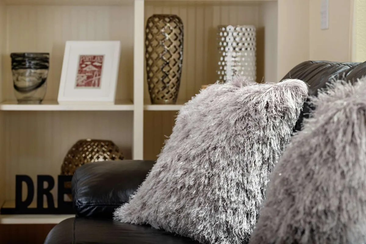 A cozy living area with fluffy throw pillows, decorative vases, and framed artwork. The space feels comfortable and inviting, ideal for unwinding after a productive day.